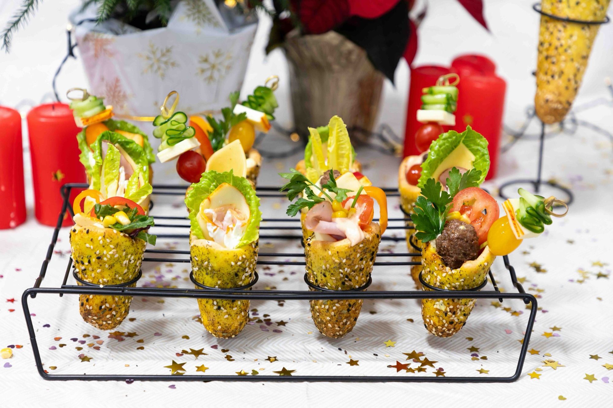 Mini BreadKones filled with ham, cheese, and vegetable skewers in a wire rack on a festive table