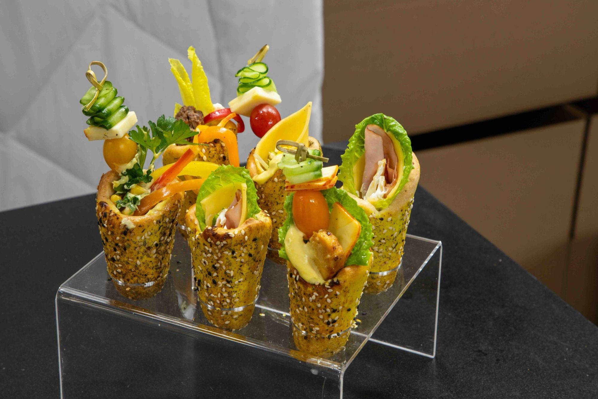 Mini BreadKones with vegetable and cheese skewers on a clear acrylic riser