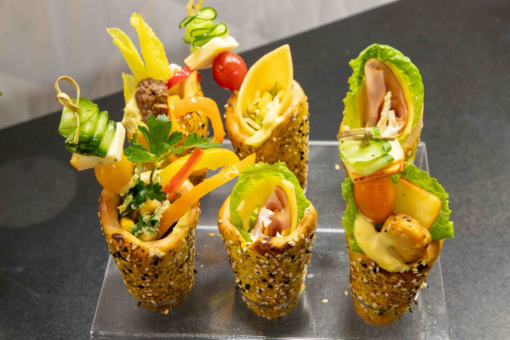 Six mini BreadKones with meatball, ham, and vegetable fillings on an acrylic stand