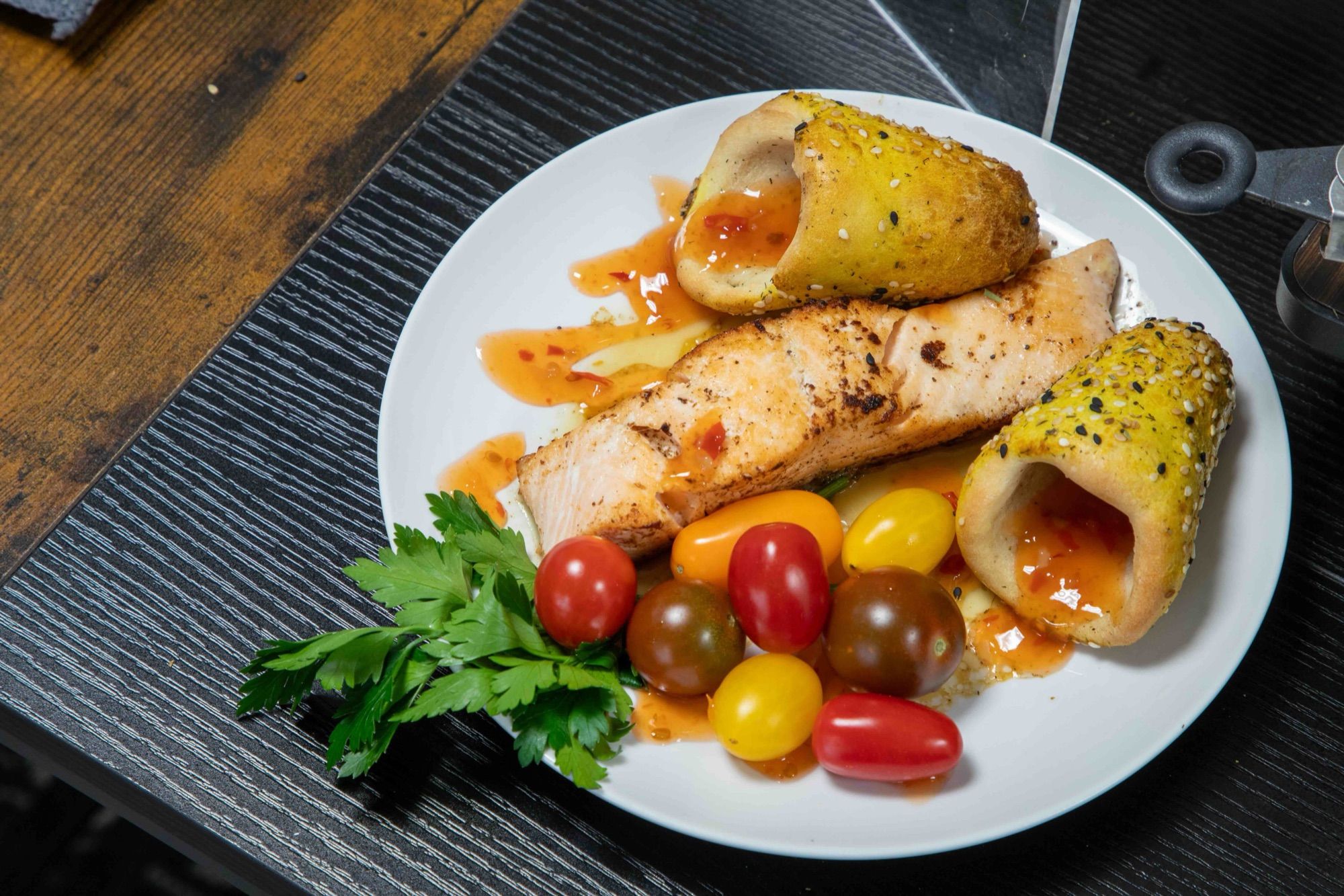 Grilled salmon plated with two BreadKones, heirloom cherry tomatoes, and parsley