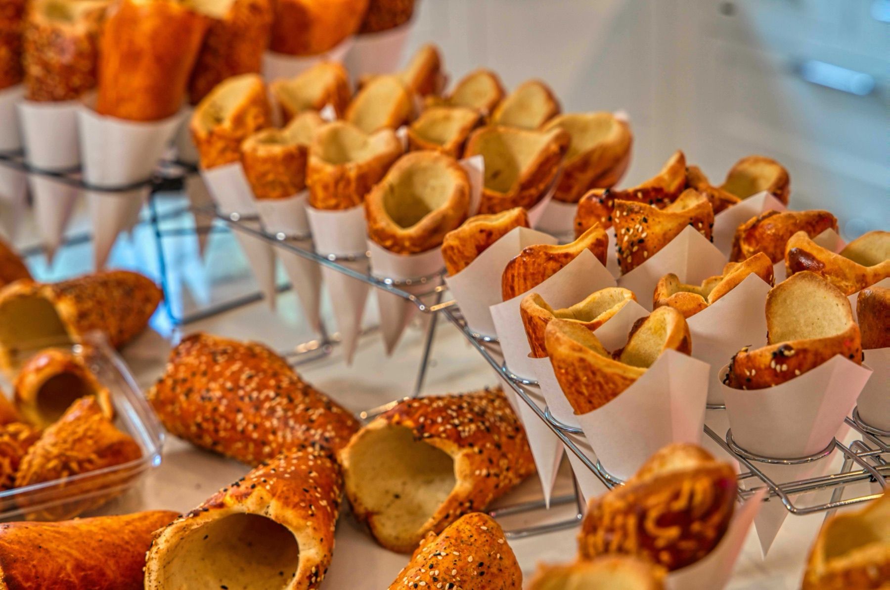 Sesame-topped BreadKones standing in paper cones on wire racks