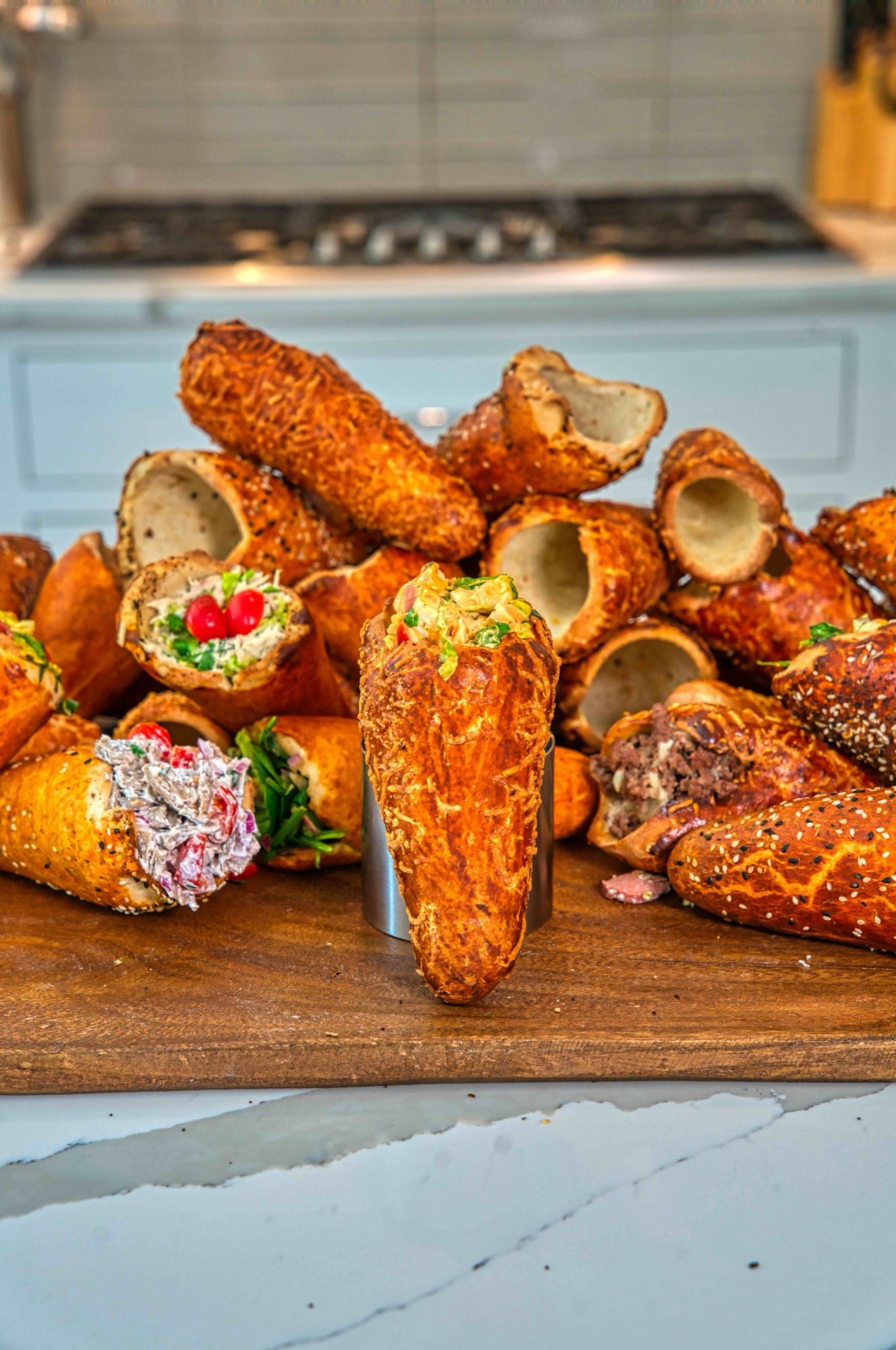 A pile of BreadKones with assorted fillings on a wooden board