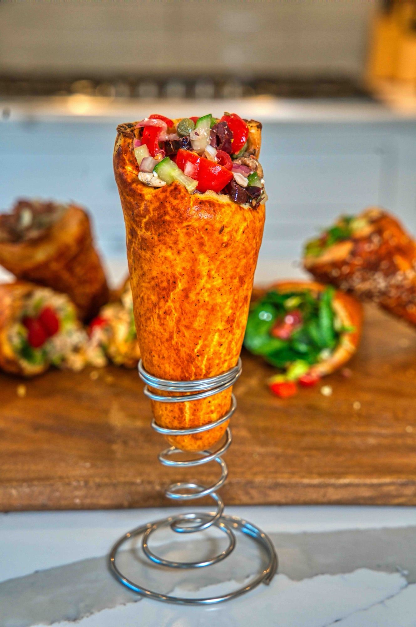 A BreadKone filled with Greek salad standing in a spiral holder