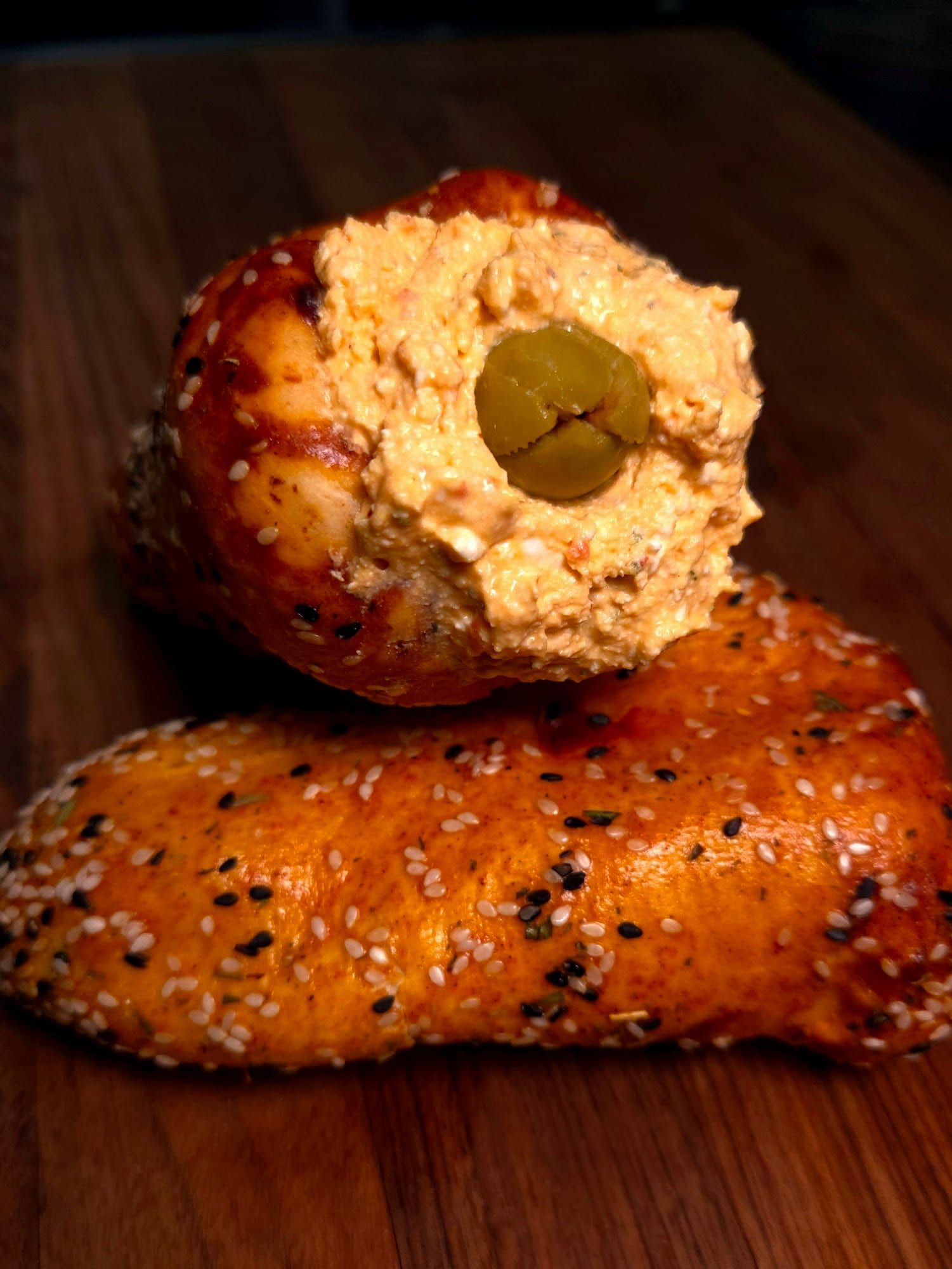 Close-up of a sesame BreadKone filled with salad and topped with a green olive