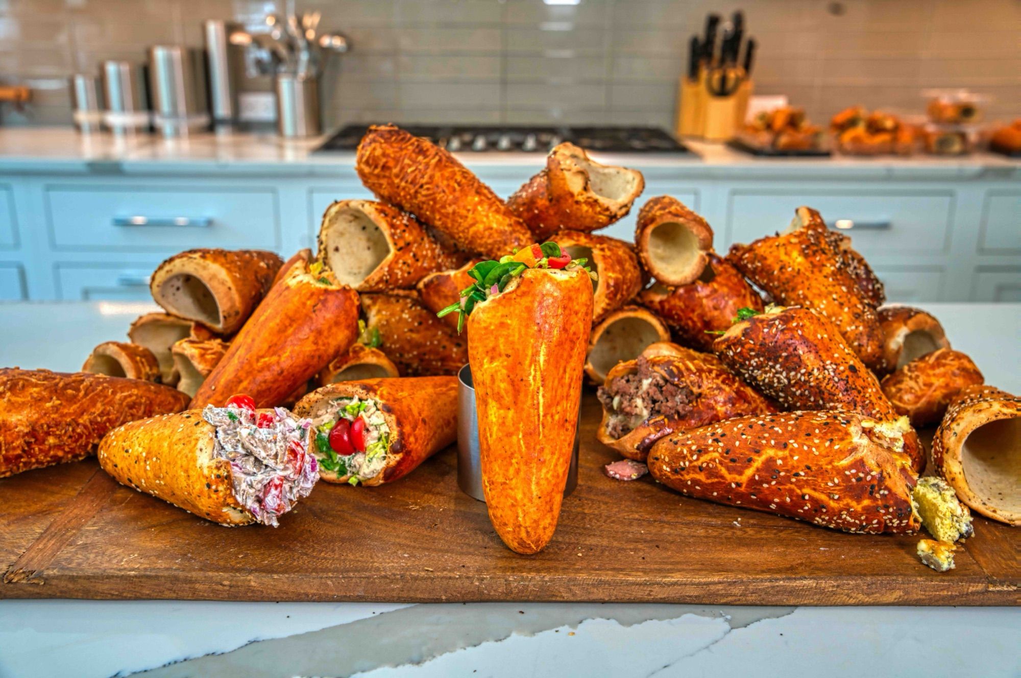 BreadKones with chicken salad, spinach, beef, and tuna fillings laid out on a wooden board