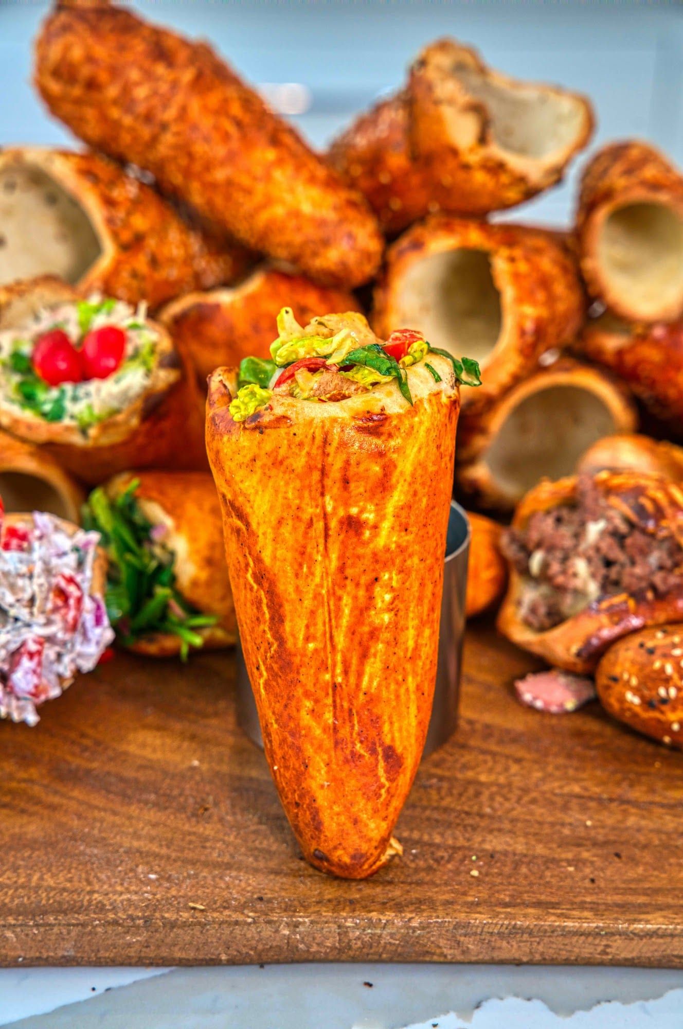 A Parmesan BreadKone filled with salad among a pile of filled and empty cones